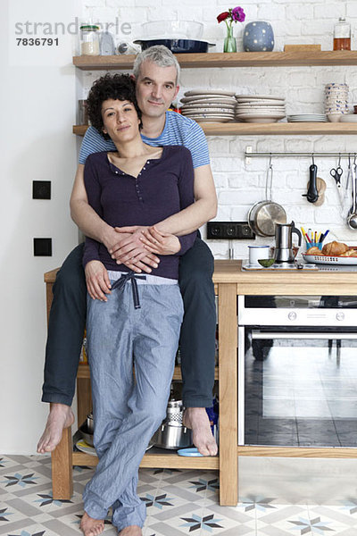 Ein liebevoll lächelndes  altersgemischtes Paar in der Küche