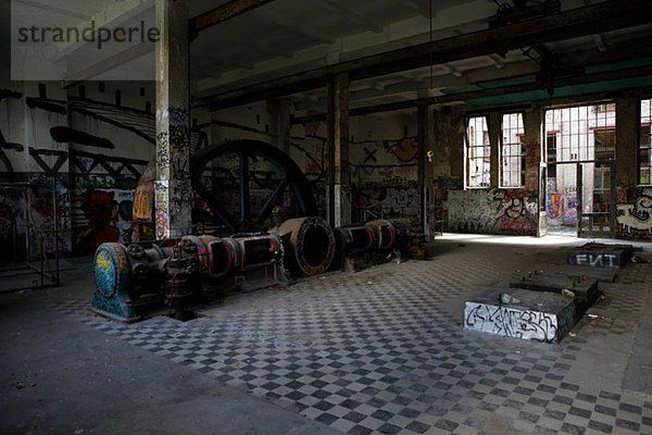 Innenansicht eines verlassenen Industriegebäudes mit Graffiti an den Wänden