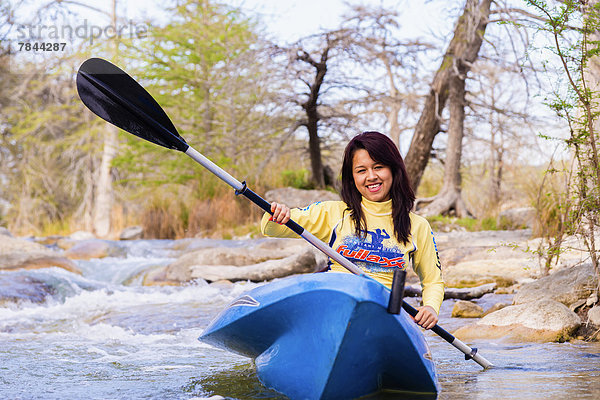 USA  Texas  Junge Frau beim Kajakfahren auf dem Frio River  lächelnd