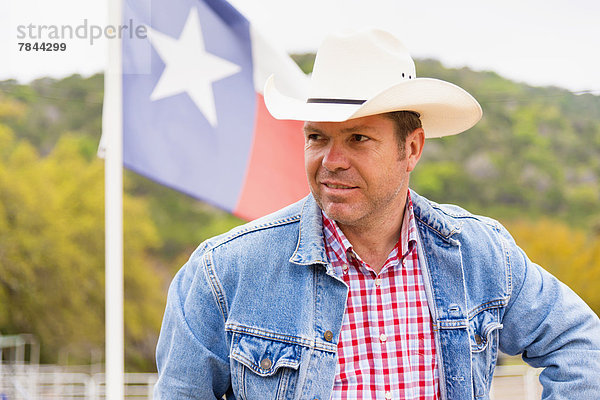 Texas  Erwachsener Mann vor der Fahne mit Cowboyhut