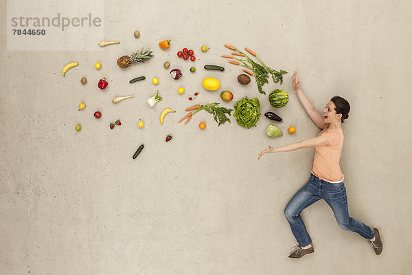 Frau mit Obst und Gemüse vor beigen Hintergrund