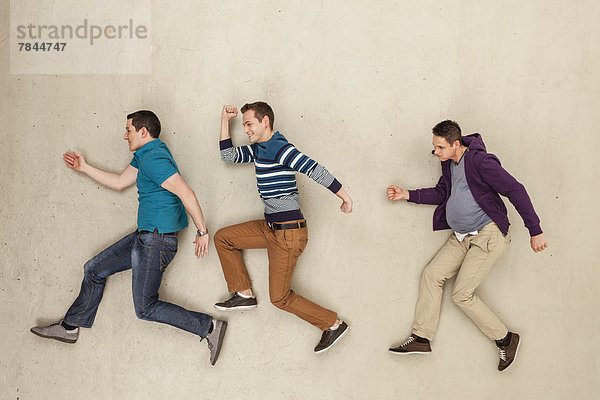 Männer laufen auf beigefarbenem Hintergrund