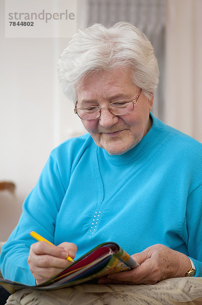 Seniorin beim Kreuzworträtsel  lächelnd