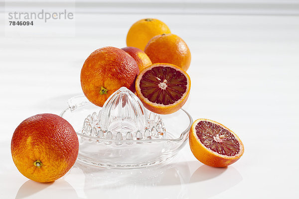 Blood oranges with juice extractor on white background  close up