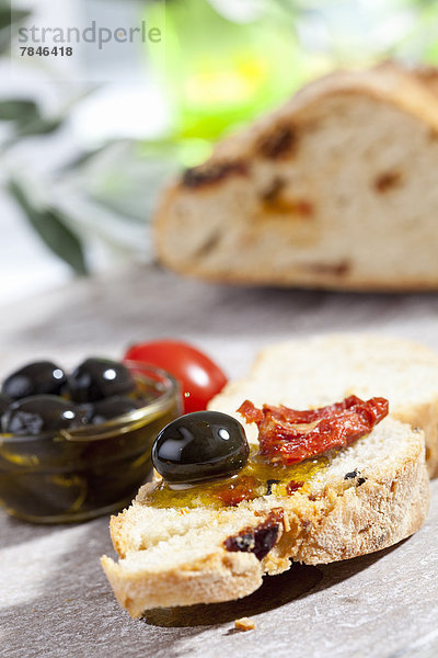 Slice of bread with olive and dried tomato  close up