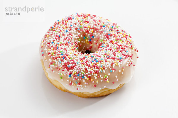 Doughnut topped with icing and sprinkles on white background  close up