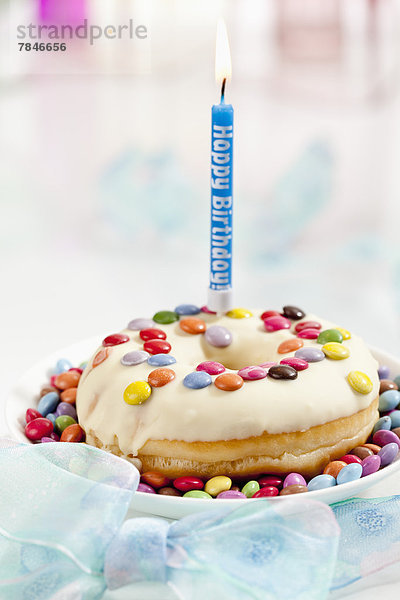 Doughnut with illuminated birthday candle  close up