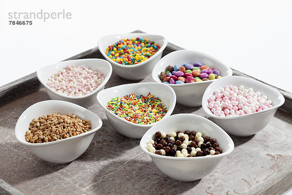 Variety of sprinkles in bowl on wooden tray  close up