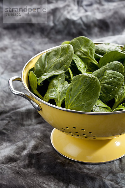 Spinach leafs in yellow colander  close up