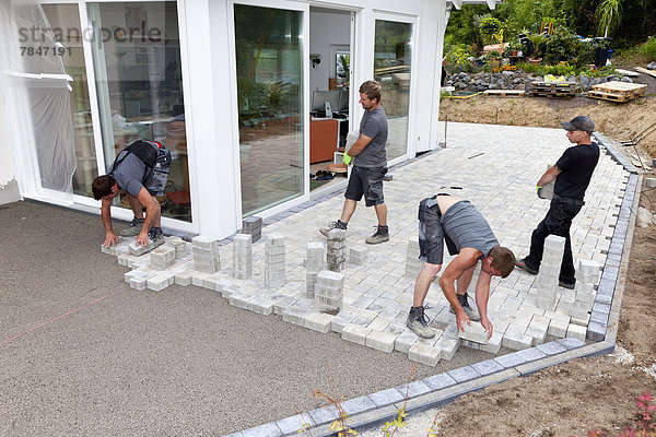 Germany  Rhineland Palatinate  Young men assembling paving stones