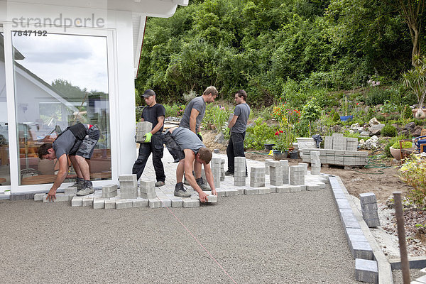 Germany  Rhineland Palatinate  Young men assembling paving stones