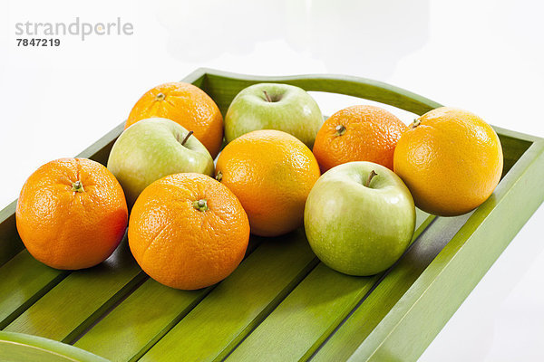 Green apples and oranges on wooden tray  close up