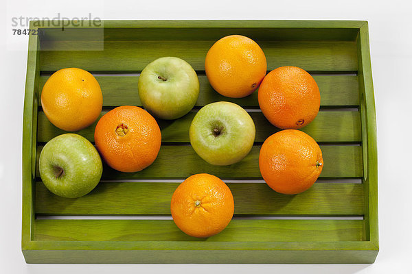 Grüne Äpfel und Orangen auf Holztablett  Nahaufnahme