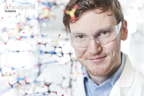 Deutschland  Porträt eines jungen Wissenschaftlers mit DNA-Modell  lächelnd