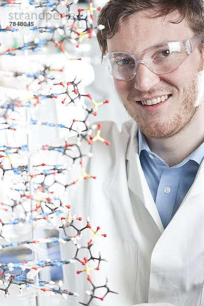 Deutschland  Porträt eines jungen Wissenschaftlers mit DNA-Modell  lächelnd
