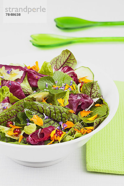 Salat in Schüssel mit Serviette und grünem Plastiklöffel  Nahaufnahme