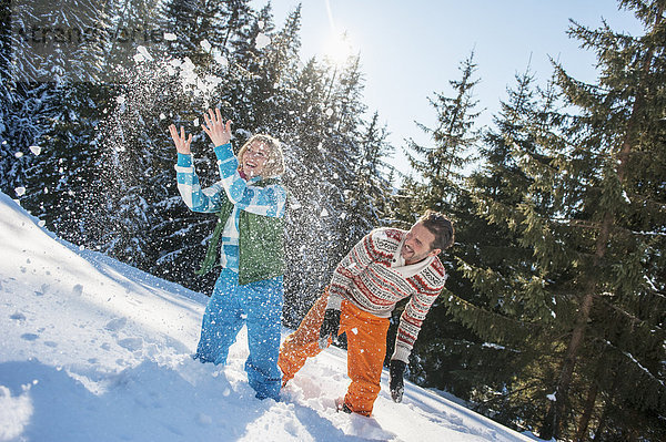 Österreich  Salzburg  Paar mit Spaß im Schnee  lächeln
