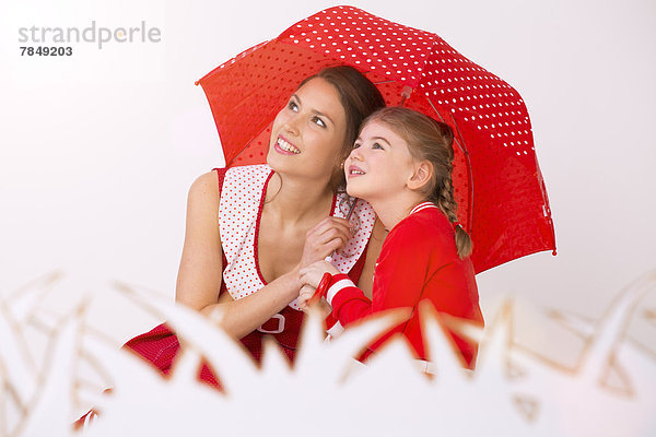 Mutter und Tochter unter dem Schirm  lächelnd