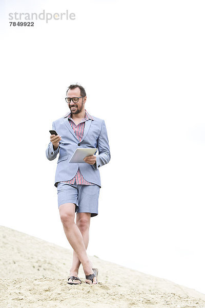 Deutschland  Bayern  Geschäftsmann mit Handy und digitalem Tablett  lächelnd