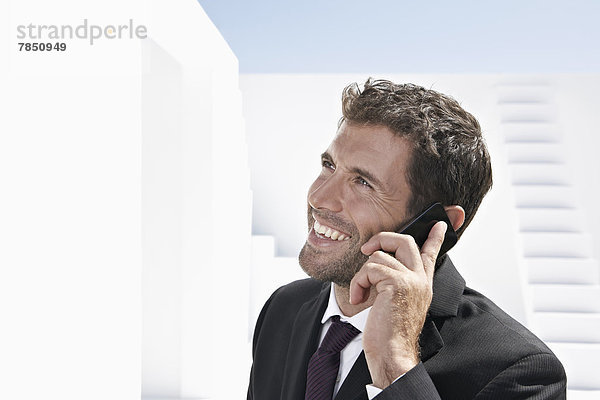 Geschäftsmann im schwarzen Anzug spricht auf dem Handy  lächelnd