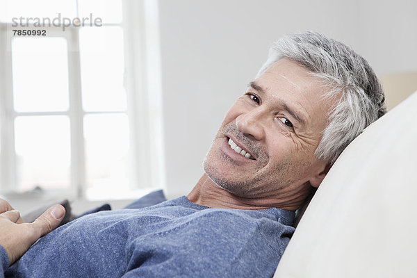Porträt eines reifen Mannes  der sich auf dem Sofa entspannt  lächelnd