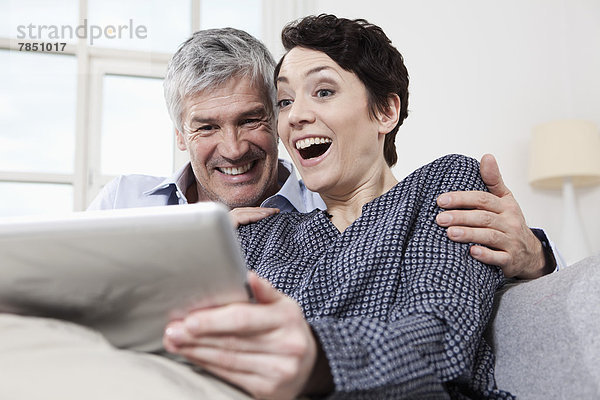 Deutschland  Bayern  München  Paar mit digitalem Tablett zu Hause  lächelnd