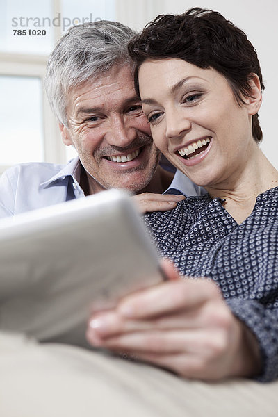 Deutschland  Bayern  München  Paar mit digitalem Tablett zu Hause  lächelnd