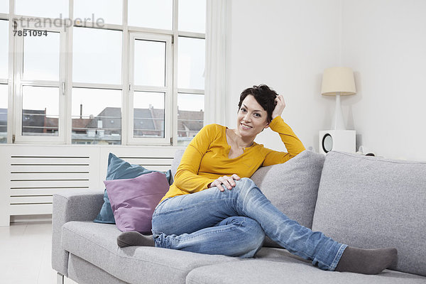 Porträt einer erwachsenen Frau auf der Couch sitzend  lächelnd