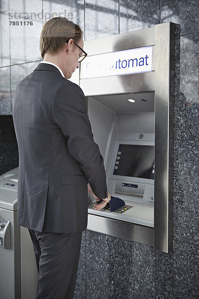 Reifer Mann am Geldautomaten am Flughafen