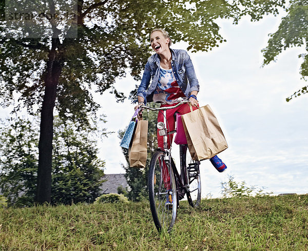 Junge Frau auf dem Fahrrad mit Einkaufstaschen