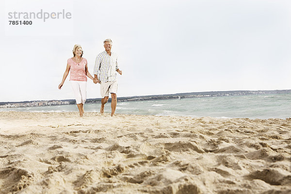 Spanien  Seniorenpaar zu Fuß am Strand von Palma de Mallorca