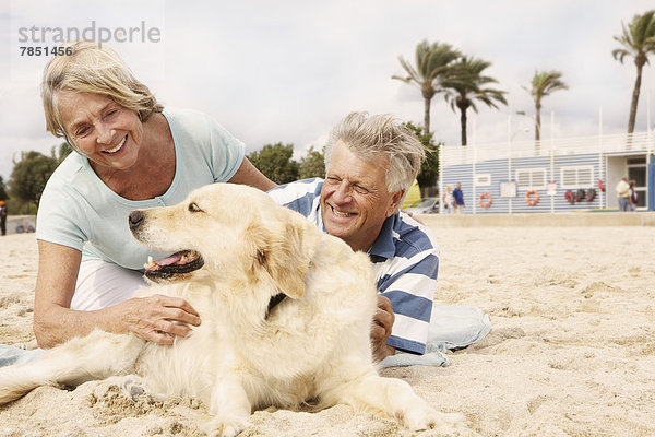 Spanien  Seniorenpaar mit Hund am Strand von Palma de Mallorca  lächelnd