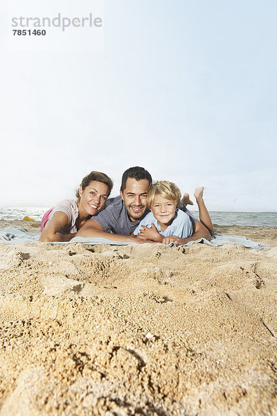 Spanien  Familie am Strand von Palma de Mallorca liegend  lächelnd