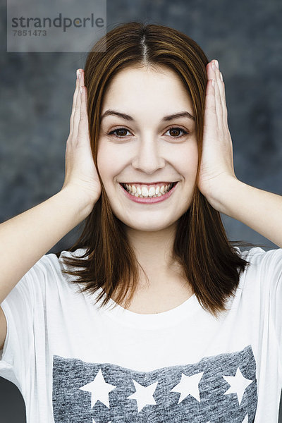 Porträt einer jungen Frau  die die Ohren bedeckt  lächelnd