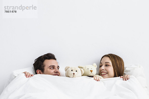 Junges Paar mit Teddybär schaut sich an  lächelnd