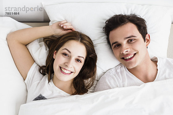 Junges Paar auf dem Bett liegend  lächelnd