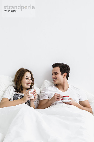 Junges Paar beim Tee im Bett  lächelnd