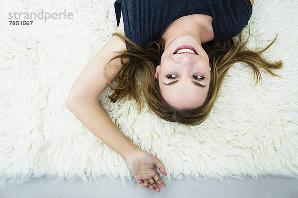 Junge Frau auf dem Teppich liegend  lächelnd
