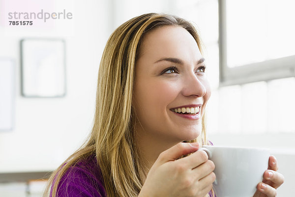 Junge Frau hält Tasse Tee  lächelnd