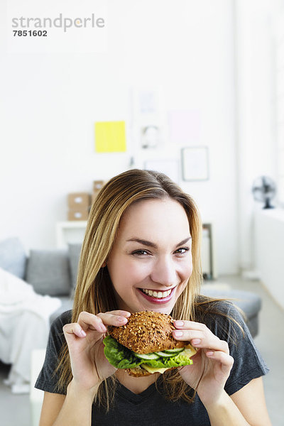 Porträt einer jungen Frau mit Burger  lächelnd