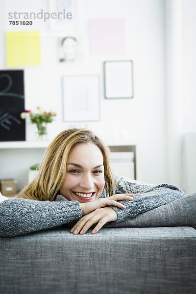 Porträt einer jungen Frau  die sich auf der Couch entspannt  lächelnd