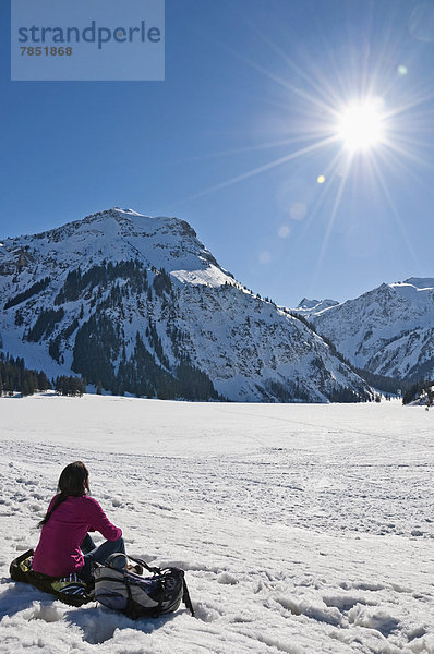 Österreich  Frau sitzend im Schnee in den Tannheimer Alpen