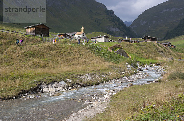 Italien  Blick auf die Pfunderer Berge und das Bergdorf mit Wanderern in Bachnähe