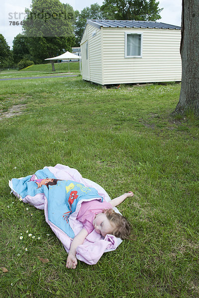 Kleines Mädchen schlafend im Schlafsack auf Gras