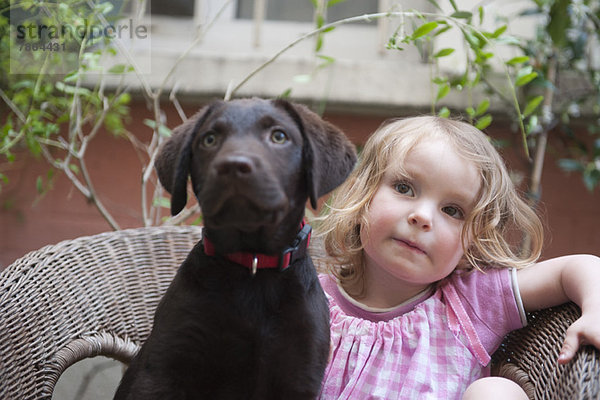 Kleines Mädchen beim Hund sitzend