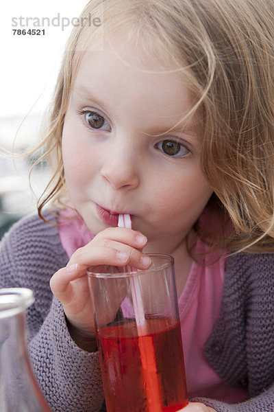 Kleines Mädchen trinkt ein Getränk mit Strohhalm