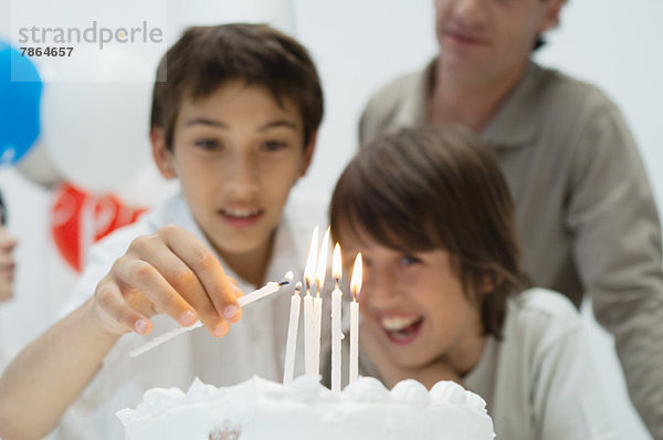 Junge zündet Kerzen auf Geburtstagskuchen an