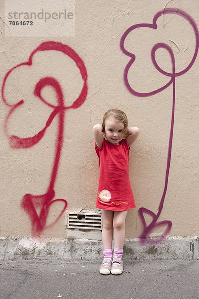 Kleines Mädchen an der Wand lehnend mit Blumengraffiti  Portrait