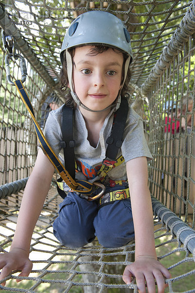 Junge klettert durch das Netz im Spielplatztunnel