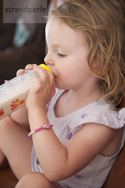 Kleines Mädchen trinkt Milch aus der Flasche  Seitenansicht